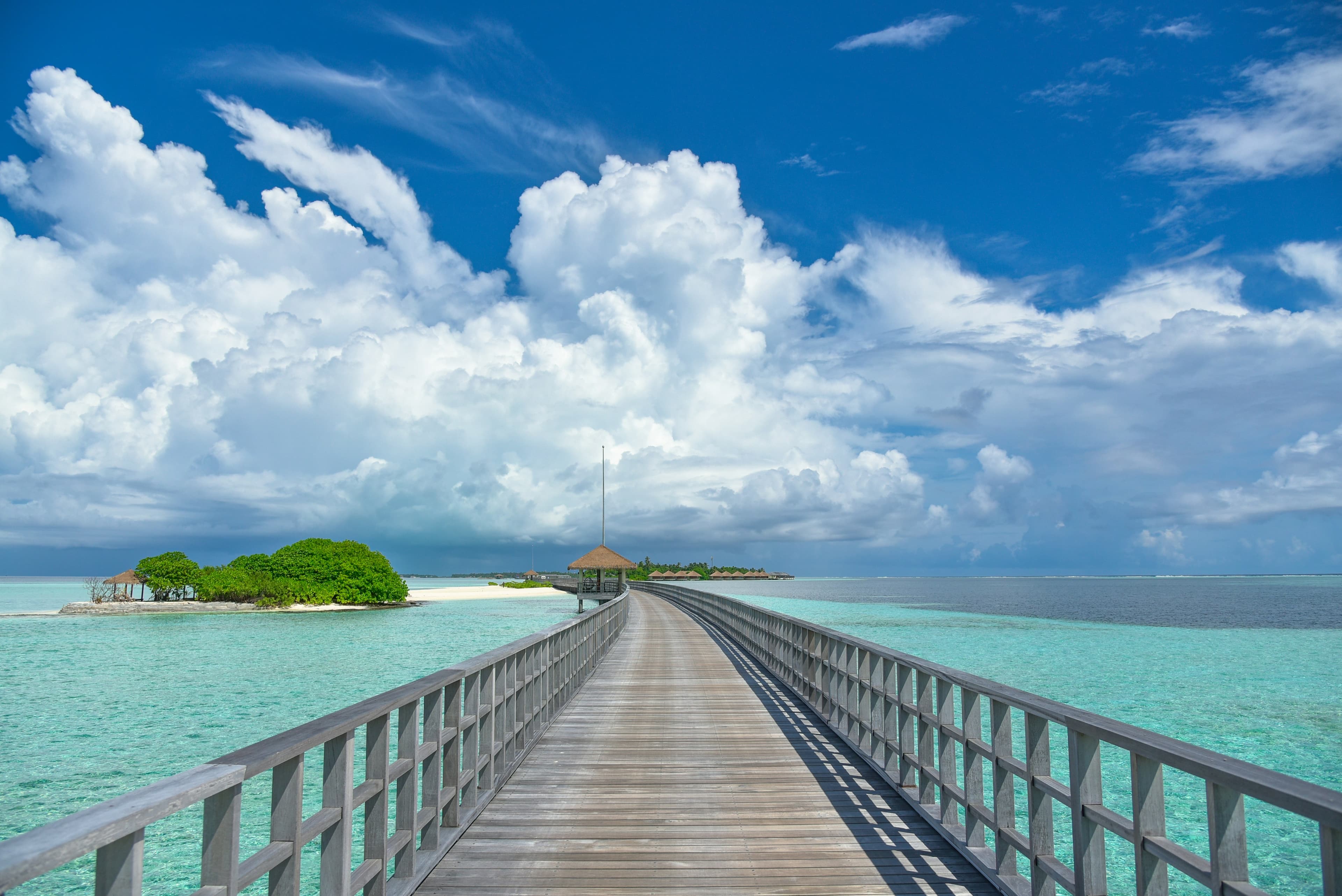 A scenic travel photo of a wooden boardwalk over turquoise tropical water